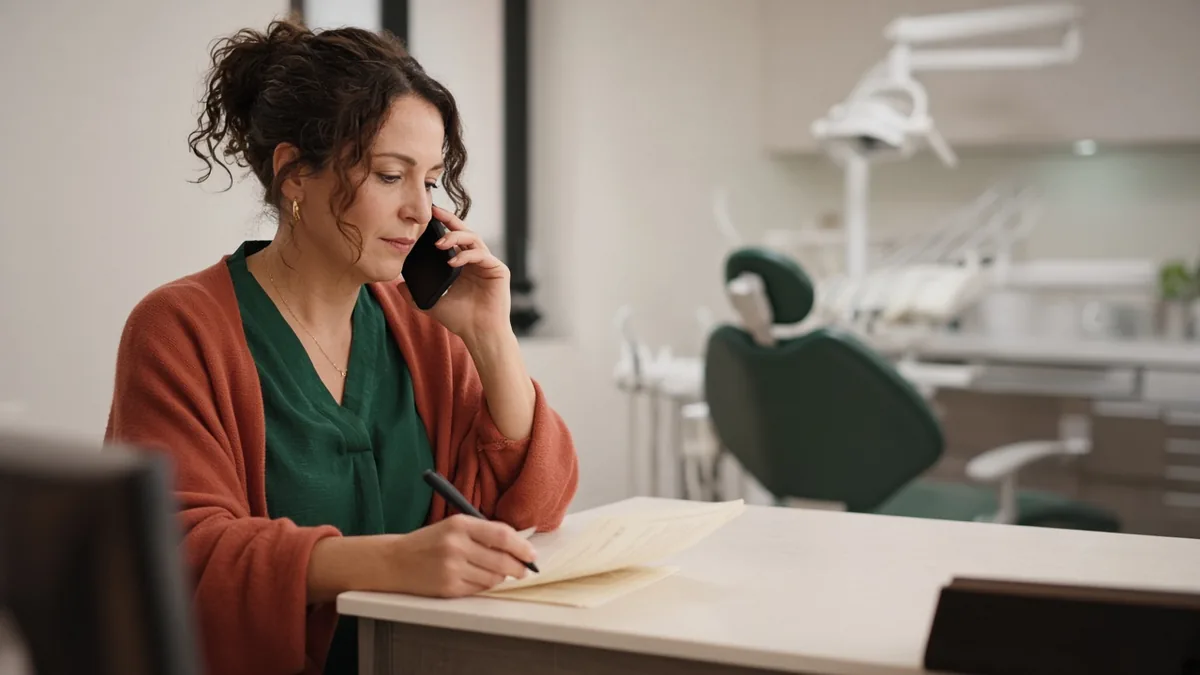 Treatment coordinator following up on a presented dental plan with an empty operatory in the background